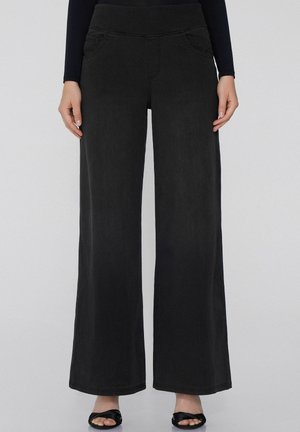 Weite schwarze Jeans mit glatter Textur, ausgestattet mit Vordertaschen und einem hohen, elastischen Bund für Komfort und Stil.