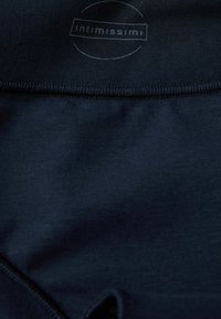 Mörkblått tyg med en slät yta och kontrasterande sömmar. Logotypen "intimissimi!" syns i en cirkulär design nära toppen.