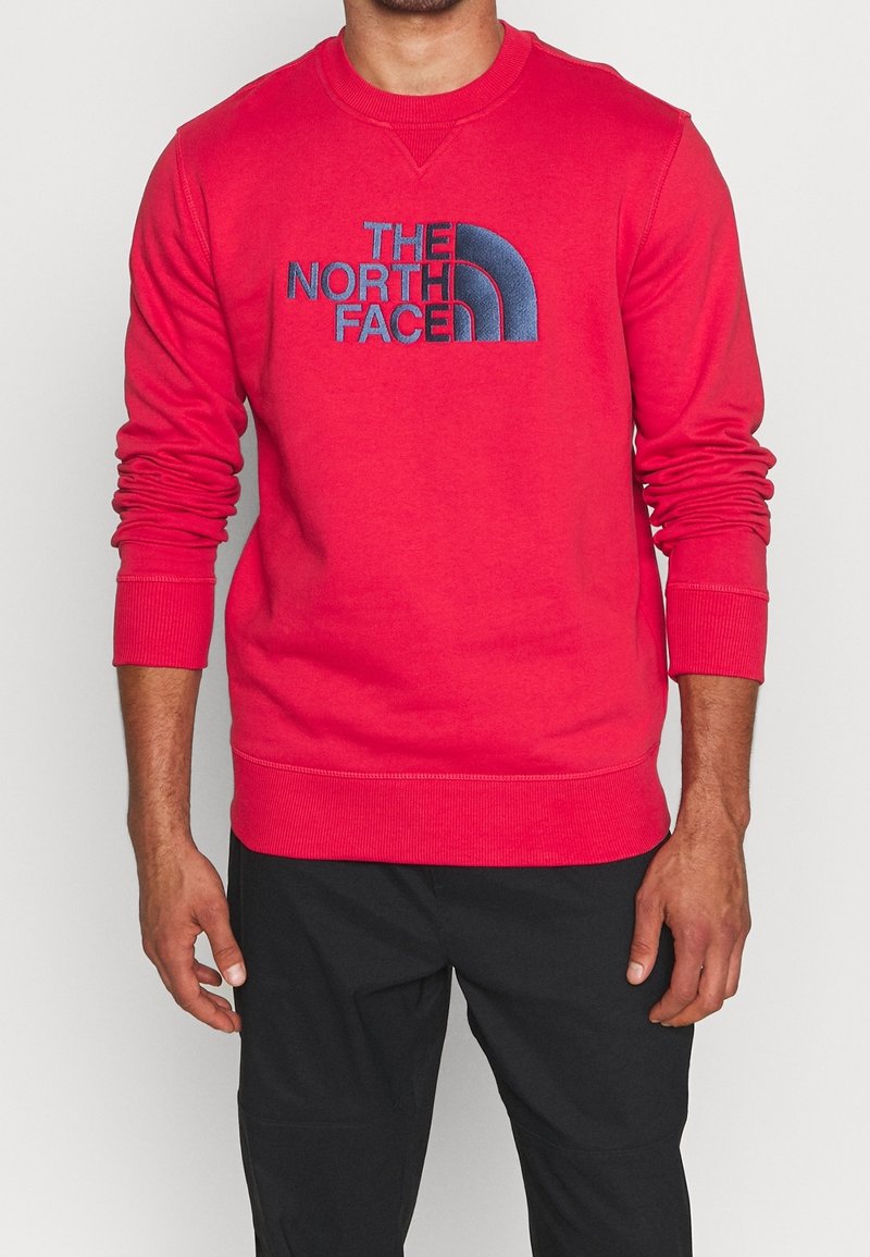 Czerwony sweatshirt z niebieskim haftem logo "THE NORTH FACE". Zaprojektowany z długimi rękawami oraz ściągaczami w mankietach i u dołu dla teksturowanego wyglądu.