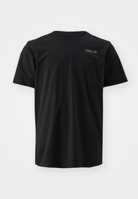 Camiseta negra de algodón con mangas cortas, cuello redondo y un pequeño acento de logo blanco en la parte superior izquierda. Textura suave, ajuste estándar.