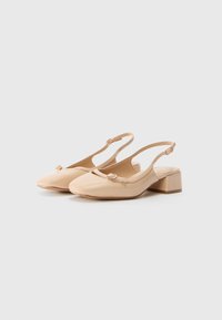 Beige lackleder Slingback-Schuhe mit runder Zehenpartie, minimalistischem Schleifendetail und niedrigem Blockabsatz. Glatte Textur im gesamten Schuh.