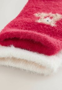 Punane ja valge kohev kudum, virnastatud. Punases osas on tekstuuriline muster, samas kui valges osas on sile pind.