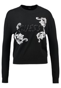 Pull noir à manches longues avec "GUESS" en lettres texturées noires et broderie florale blanche sur le devant.