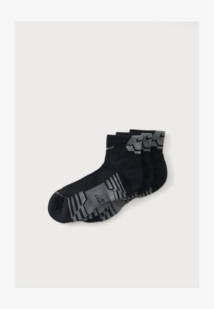 Trois paires de chaussettes de sport noires et grises avec un logo swoosh, disposées en chevauchement sur un fond blanc.