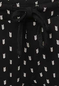 Calças joggers pretas em tecido com padrões brancos de seta, apresentando uma cintura com cordão e uma textura suave. Design focado nos detalhes com um estilo casual.