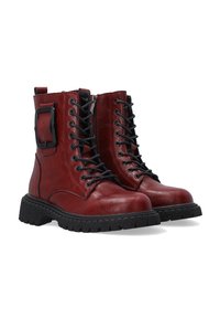 Red leather ankle boots with black laces, a zip closure, and a side buckle. Textured black rubber sole and rounded toe design.