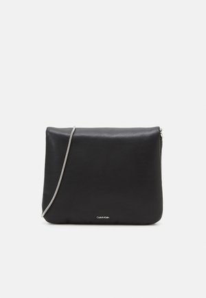 Zwarte rechthoekige leren clutch met dunne zilveren kettingriem en klein Calvin Klein-logo onderaan in het midden.