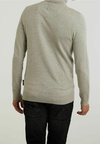Pull gris en maille avec col montant, ourlet côtelé et manches longues ; présente un détail de design à l'arrière et une étiquette noire en bas.