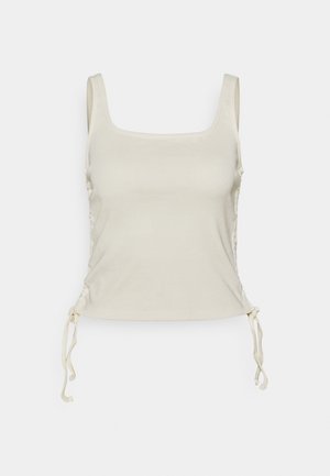 Top in beige chiaro con scollatura quadrata, coulisse regolabili ai lati e una texture liscia e morbida.