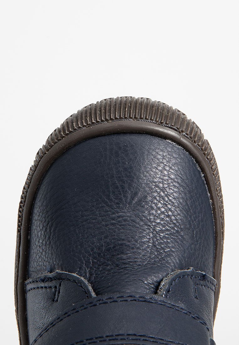 Marineblaue Lederschuhe mit runder Zehenform und strukturierter Oberfläche. Sie verfügen über eine dicke braune Gummisohle mit Rillen.