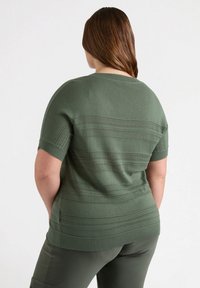 Groene korte mouwen gebreide top met horizontale strepen, geribbelde halslijn en een ontspannen pasvorm. G draag met bijpassende groene broek.