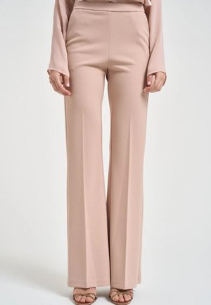 Pantaloni beige a vita alta e gamba larga indossati con top a maniche lunghe abbinato e sandali dorati con listini.