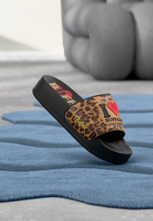 Black platform slide sandal with leopard print strap reading "I heart Buffalo," displayed on a textured blue rug with blurred gray cushions in background.