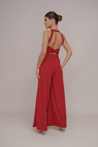 Combinaison rouge avec des jambes larges et un dos nu, dotée d'un design noué et d'une fermeture à bouton au niveau du cou. Tissu lisse et extensible.