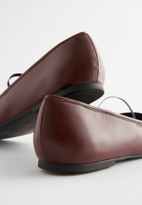Bordowe skórzane baletki z wydłużonym noskiem i płaską czarną gumową podeszwą. Gładka faktura, elegancki design i minimalne detale.