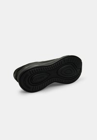 Fekete sneaker, textúrált gumitalppal, sima felsőrésszel. A talpon ívelt minták és márkázás található.