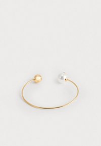 Bracciale in cuff d'oro con una sfera d'oro lucido a un'estremità e una perla bianca lucida dall'altra, con una banda in metallo sottile e liscia.