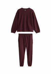 Burgundy loungewear set made of ribbed material, featuring a long-sleeve top with a crew neck and matching tapered pants with an elastic waistband.