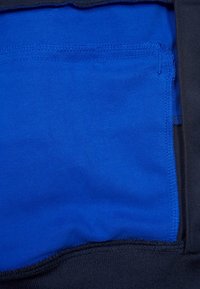 Svart tyg med en slät yta har ett blått innerfoder. Kanterna är snyggt sydda, vilket ger en distinkt färgkontrast.