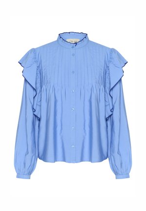 Gaiši zila krekla blūze ar volāniem pie piedurknēm, krokotām frontēm un noapaļotu apkakli. Izceļas ar mīkstu, gludu audumu ar smalku spīdumu.