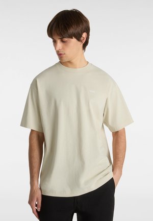 Lys beige bomulds T-shirt med afslappet pasform, korte ærmer og rund hals. Har et lille hvidt logo på venstre bryst.