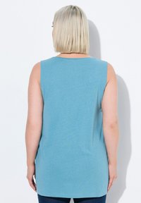 Top senza maniche di colore blu chiaro con scollatura rotonda, realizzato in tessuto morbido; presenta una vestibilità rilassata e scende sotto i fianchi.