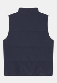 Tmavě modrá prošívaná vesta bez rukávů s vysokým límcem, prošitým designem a staženým lemem pro větší teplo a pohodlí. Bez viditelných kovových prvků.