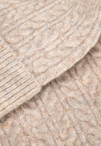 Béžový pletený svetr s texturovaným copánkovým vzorem. Má žebrované manžety a viditelné švy, vyrobený z měkké vlny.