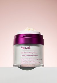 Murad Heartleaf Calming Cream i en genomskinlig burk med ett vitt lock och lila detaljer. Krämig konsistens syns från locket. Text på burken.
