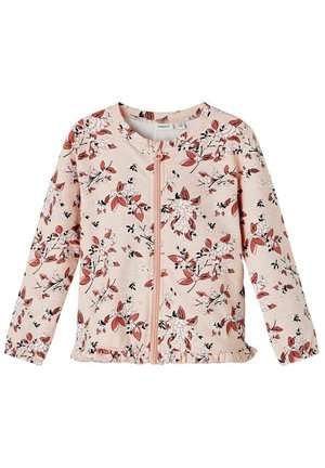 Chaqueta rosa claro con cremallera, estampado floral en rojo y blanco, mangas largas, dobladillo fruncido y textura de tela suave.