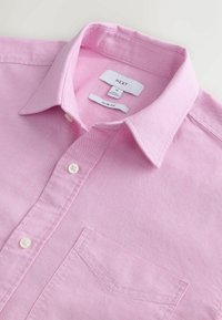 Vaaleanpunainen slim fit -paita, jossa on nappikaulus. Paidassa on rintatasku ja valkoiset napit. Valmistettu teksturoidusta kankaasta. Kauluksessa on etiketti.
