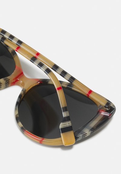Lunettes de soleil à forme angulaire, fabriquées en plastique multicolore avec des motifs beige, noir et rouge, dotées de verres teintés.