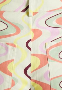 Tecido de algodão com padrões coloridos em espirais nas cores rosa, laranja, amarelo, verde e bordô; apresenta dois bolsos frontais para utilidade.