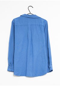 Camisa azul de manga larga en una percha, con un cuello amplio, puños abotonados y una tela suave y ligera con una textura sutil.