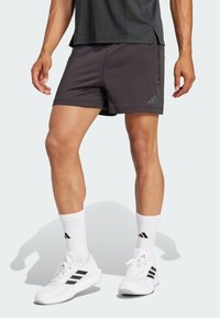 Svarte atletiske shorts laget av lett stoff, med en glidelås lomme og side-striper. Kombinert med hvite sko og sokker med svarte detaljer.
