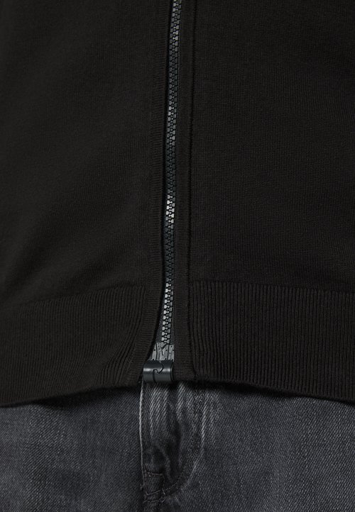Schwarzer Zip-Up-Pullover mit geripptem Saum und Bündchen, aus strukturiertem Strickstoff. Der Reißverschluss ist schwarz mit einem silbernen Ziehgriff.