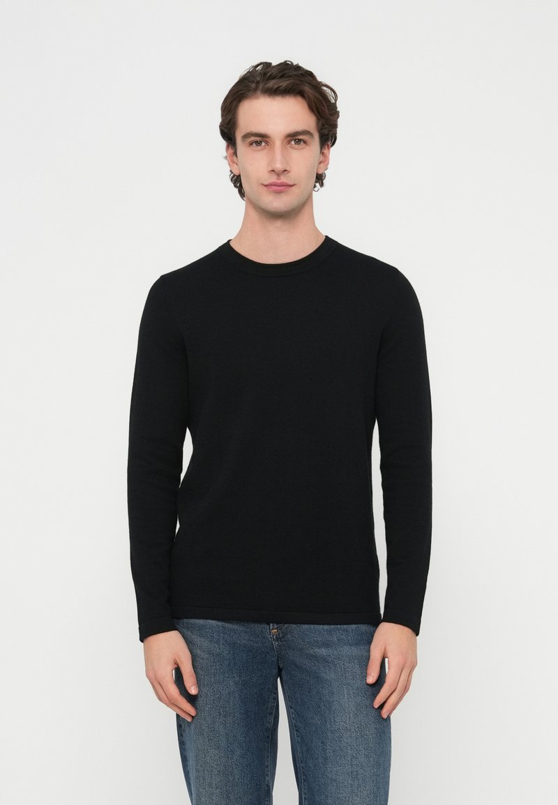 Czarny sweter z długim rękawem i okrągłym dekoltem, wykonany z miękkiej dzianiny, o dopasowanym kroju i gładkiej fakturze, zestawiony z niebieskimi dżinsami.