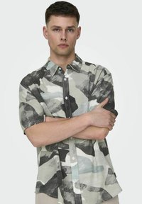Korte mouwen overhemd met knoopsluiting in een camouflagepatroon, met schakeringen van grijs, zwart en lichtblauw, met een relaxte pasvorm en zachte textuur.