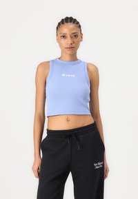 Lyseblå ribbet crop top med rund halslinning og hvit "Roxy"-logo, parret med svarte sweatpants med snøring.