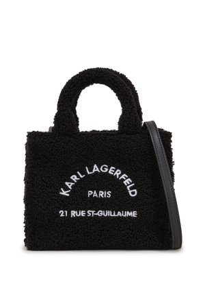 Svart plysshåndbag med korte håndtak og avtakbar skulderrem. Har brodert hvit tekst, myk tekstur og strukturert design.