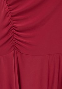 Tissu rouge profond avec un détail froncé sur un côté et un matériau fluide et lisse en dessous.