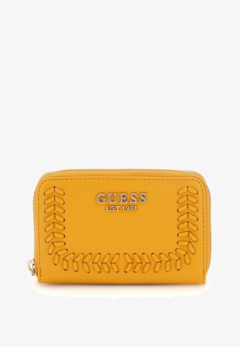 Yellow leather wallet with embossed stitching detail and silver hardware. Features "GUESS EST 1981" logo prominently on the front. Zipper closure.