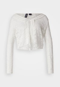 White cropped lace top with long sleeves, V-neckline, and tie closure. Floral pattern throughout, featuring a soft, textured surface.