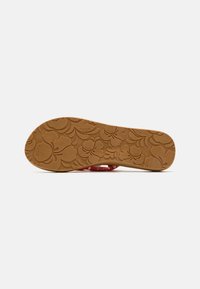 Brown rubber sole with floral pattern, featuring a red upper strap design. The sole has textured details and a Roxy logo.