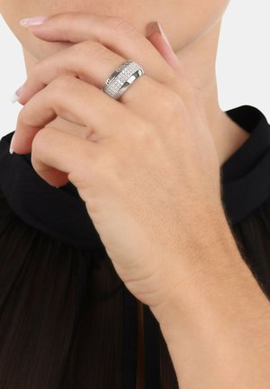 Set van zilveren ringen met gestructureerde en gladde banden, die een gepolijste afwerking met ingewikkelde details tonen, gedragen op een hand met een neutrale manicure.