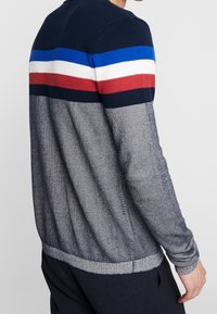 Navyblaues Strickpullover mit horizontalen Streifen in Blau, Weiß, Rot und Dunkelblau. Gerippte Bündchen und Saum mit einem strukturierten Muster.