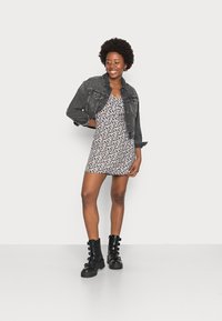 Vestuário com padrão floral, com decote em V, por baixo de uma jaqueta de ganga preta cropped. Combinado com botas de combate pretas com detalhes em tiras.