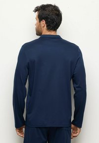 Camisa de manga larga navy hecha de una tela suave, con un collar sutil y un diseño ajustado, costuras visibles y una textura ligera.