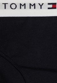 Boxer shorts neri in cotone con un elastico bianco in vita riportante la scritta "TOMMY" e un accento a logo rettangolare rosso e blu.