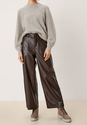 Maglione grigio lavorato a maglia, pantaloni ampi in ecopelle marrone, e stivali beige con lacci e suola spessa. Design semplice e testurizzato.